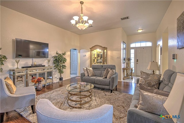 living room with dark hardwood / wood-style flooring, an inviting chandelier, and a textured ceiling