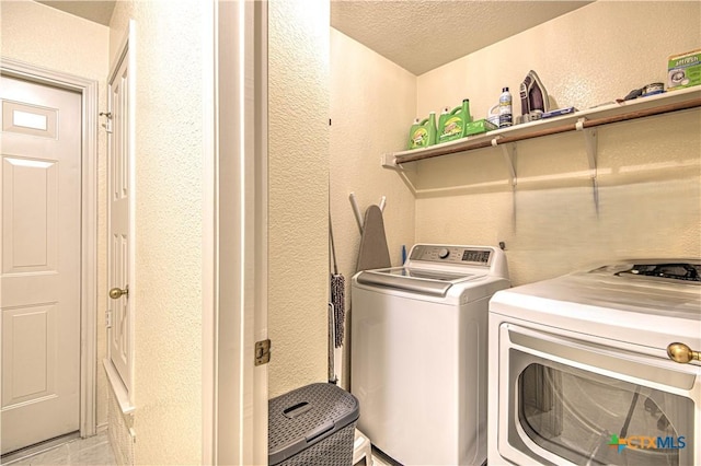 clothes washing area with washer and clothes dryer and a textured ceiling