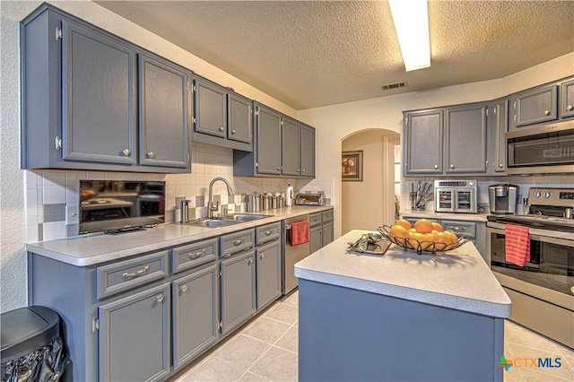 kitchen with sink, decorative backsplash, light tile patterned flooring, and appliances with stainless steel finishes