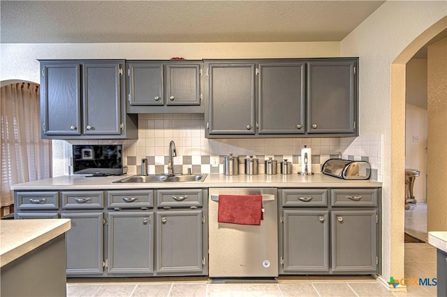 kitchen featuring gray cabinets, sink, stainless steel dishwasher, and backsplash