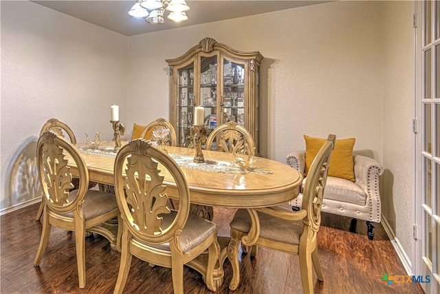 dining space with dark hardwood / wood-style floors and a notable chandelier