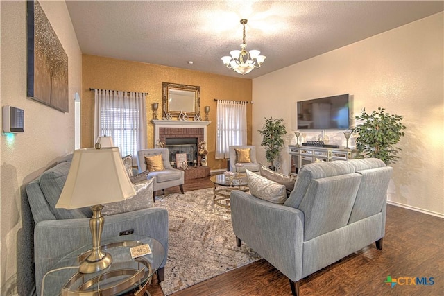 living room with dark wood-type flooring, a wealth of natural light, a textured ceiling, and a notable chandelier