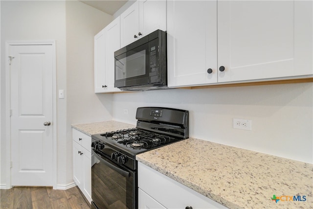 kitchen featuring black appliances, white cabinetry, light stone countertops, and light wood-type flooring