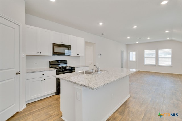 kitchen featuring black appliances, white cabinetry, sink, and an island with sink