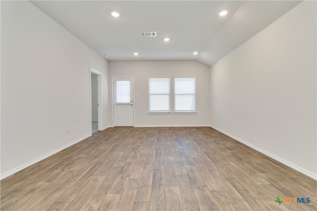 spare room with wood-type flooring and vaulted ceiling