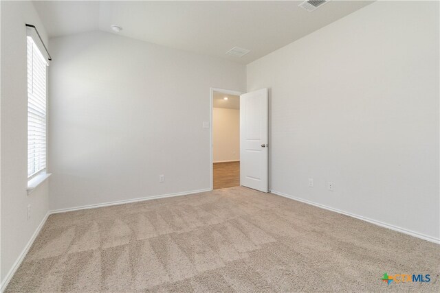 carpeted empty room featuring vaulted ceiling