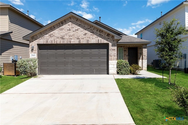 view of front of house featuring a garage, cooling unit, and a front lawn