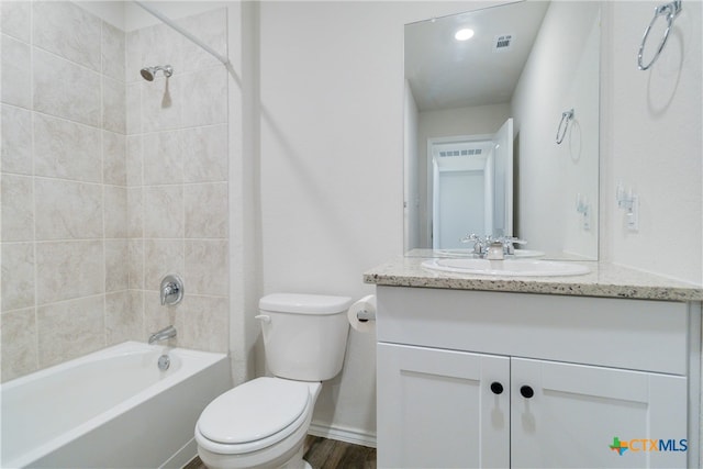 full bathroom with wood-type flooring, tiled shower / bath combo, toilet, and vanity