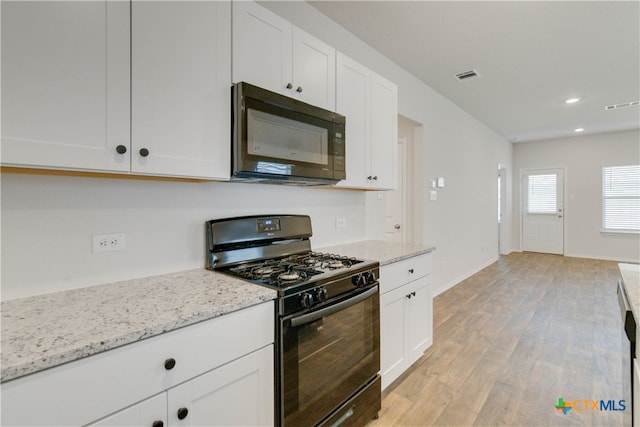 kitchen with white cabinetry, light hardwood / wood-style floors, black appliances, and light stone counters