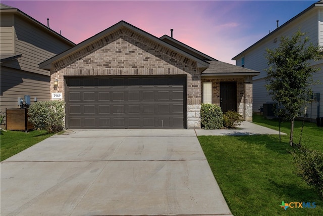 view of front of home featuring central air condition unit, a lawn, and a garage