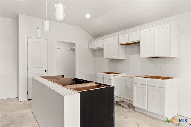 kitchen with lofted ceiling, a center island, white cabinets, and decorative light fixtures