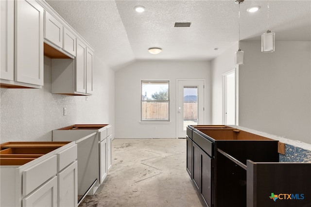 kitchen with a textured ceiling, vaulted ceiling, white cabinetry, and hanging light fixtures