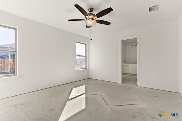 unfurnished bedroom featuring multiple windows, ceiling fan, and a spacious closet