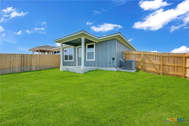 back of property with a yard and central AC