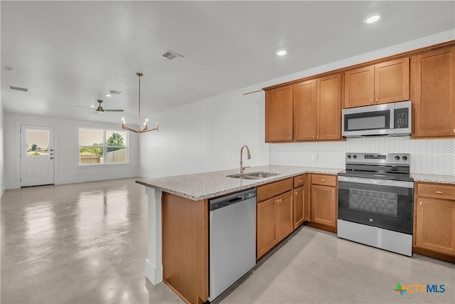 kitchen with sink, backsplash, light stone counters, kitchen peninsula, and stainless steel appliances