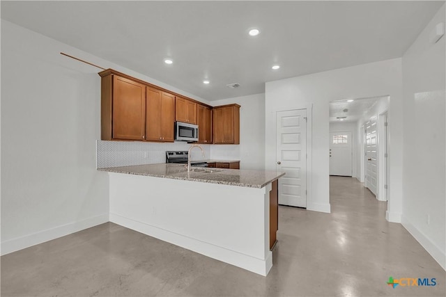 kitchen with sink, kitchen peninsula, stainless steel appliances, light stone countertops, and decorative backsplash