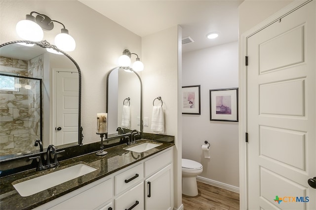 bathroom featuring hardwood / wood-style floors, walk in shower, vanity, and toilet