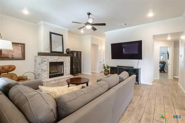 living room featuring light wood-type flooring, ceiling fan, crown molding, and a fireplace