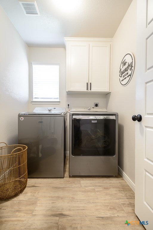 clothes washing area with light hardwood / wood-style floors, cabinets, and washing machine and clothes dryer