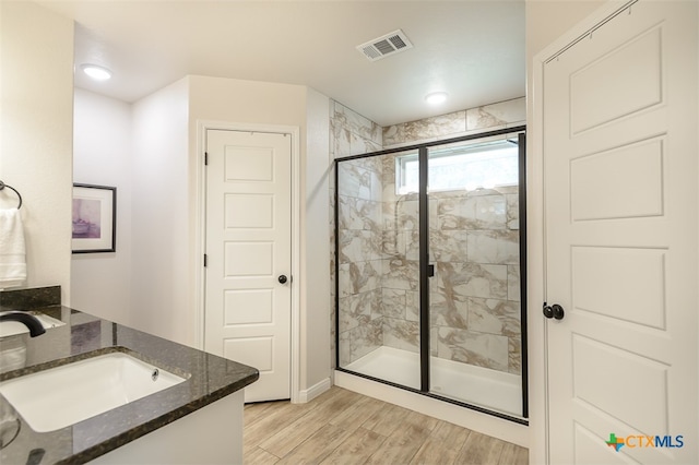 bathroom with hardwood / wood-style flooring, vanity, and an enclosed shower