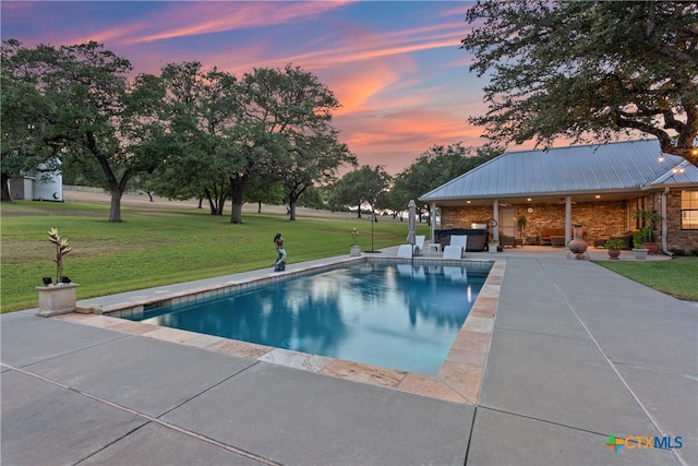 pool at dusk with a lawn and a patio area