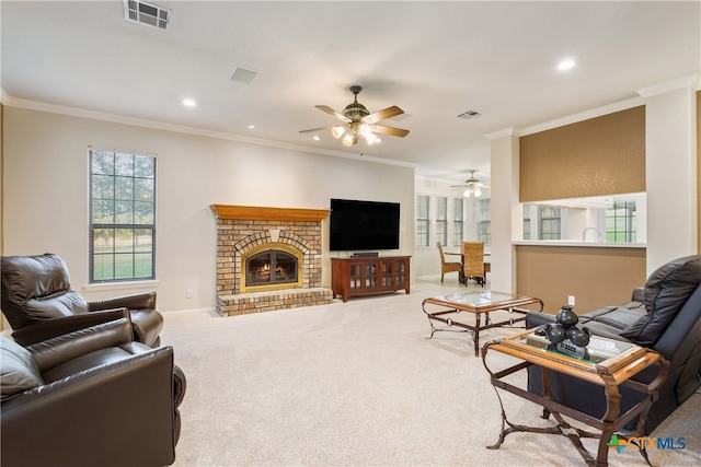 living room with a brick fireplace, ceiling fan, crown molding, and carpet floors