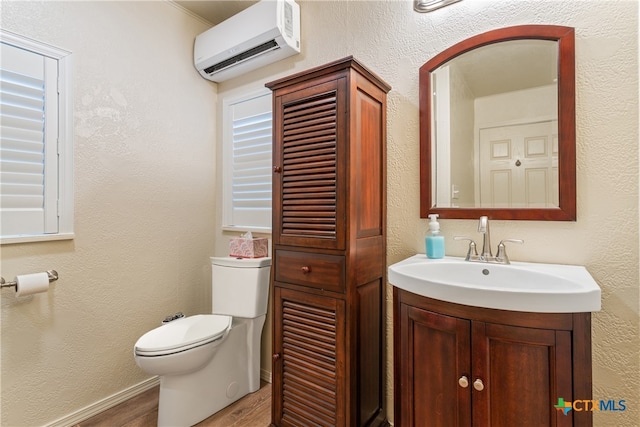 bathroom featuring hardwood / wood-style flooring, vanity, toilet, and a wall mounted air conditioner