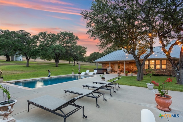 pool at dusk with a lawn and a patio