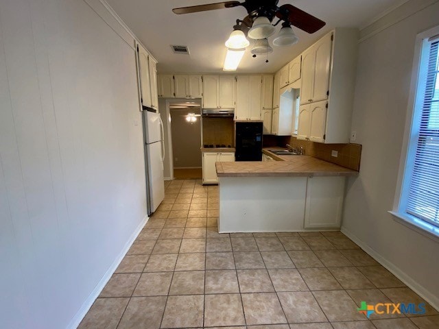 720 S Laurel Ave, Luling, TX 78648 - kitchen featuring freestanding refrigerator, a peninsula, a ceiling fan, light tile patterned floors, and white cabinets