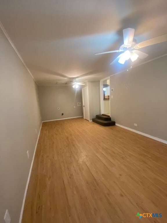 720 S Laurel Ave, Luling, TX 78648 - unfurnished living room featuring light wood finished floors, ornamental molding, and a ceiling fan