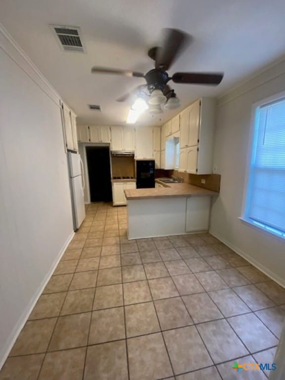 720 S Laurel Ave, Luling, TX 78648 - kitchen with a peninsula, freestanding refrigerator, ceiling fan, and light tile patterned floors