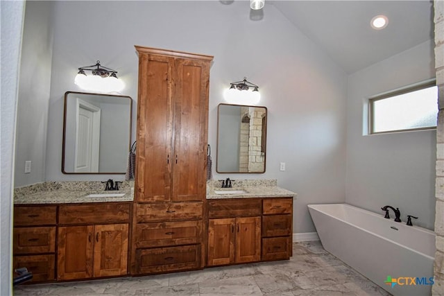 bathroom with a sink, double vanity, vaulted ceiling, a freestanding tub, and marble finish floor