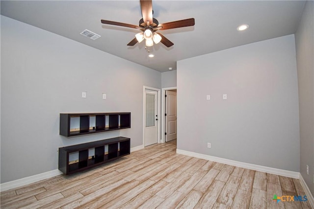 unfurnished room featuring baseboards, visible vents, wood finished floors, and a ceiling fan