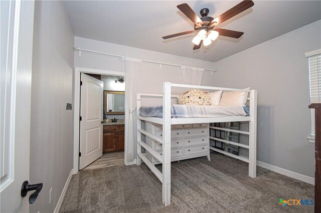 carpeted bedroom with ensuite bathroom, ceiling fan, and baseboards