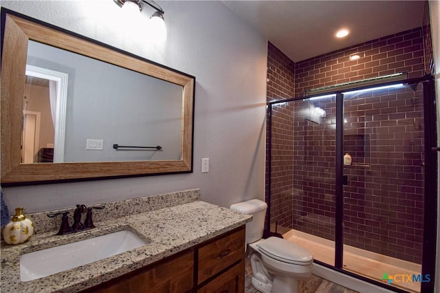 bathroom featuring toilet, a stall shower, and vanity