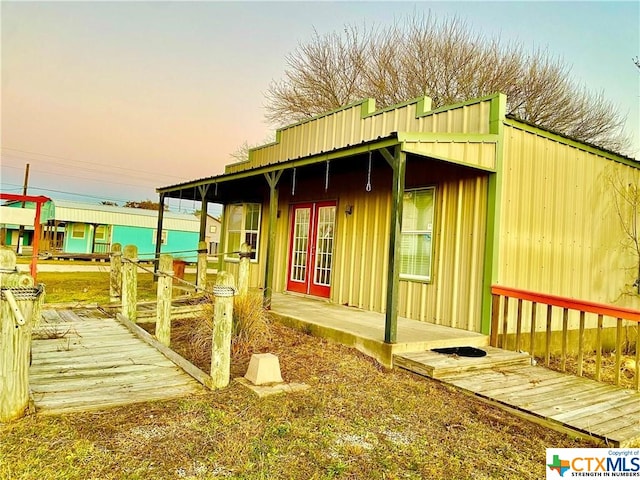 property exterior at dusk featuring french doors and a deck