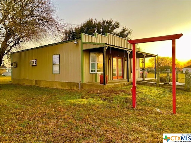 property exterior at dusk with a lawn and a wall unit AC