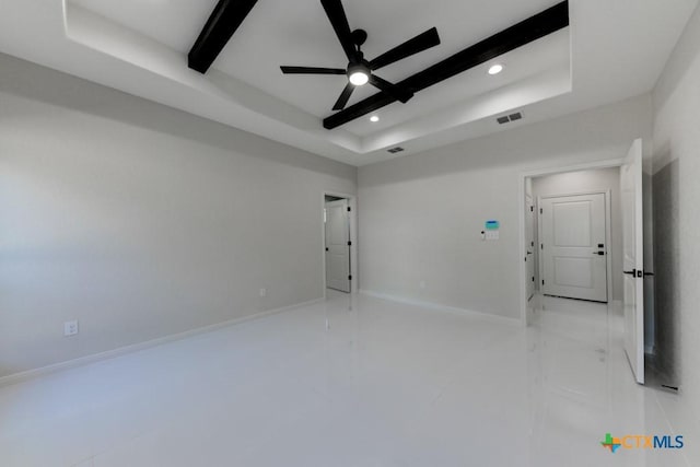 spare room featuring beamed ceiling, ceiling fan, and a raised ceiling