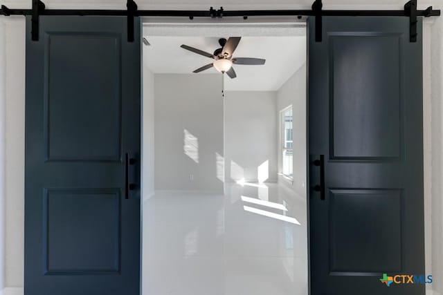 foyer entrance featuring tile patterned flooring, ceiling fan, and a barn door