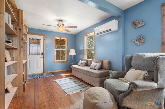 10843 US Highway 90, Harwood, TX 78632 - living area with a wall mounted AC, a ceiling fan, hardwood / wood-style flooring, and baseboards