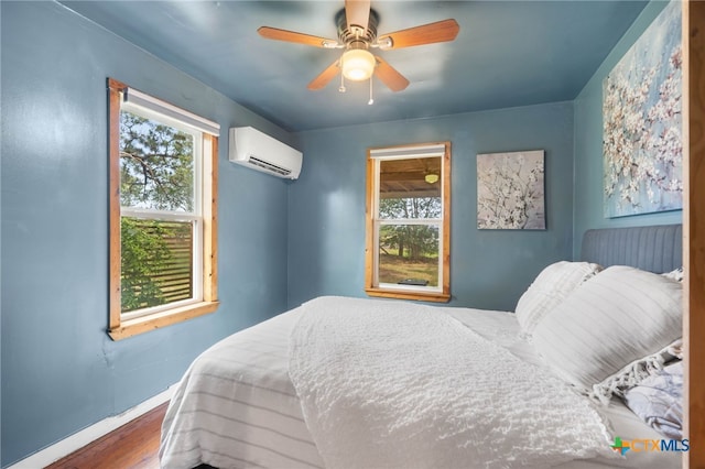 10843 US Highway 90, Harwood, TX 78632 - bedroom with a wall unit AC, wood finished floors, baseboards, and multiple windows