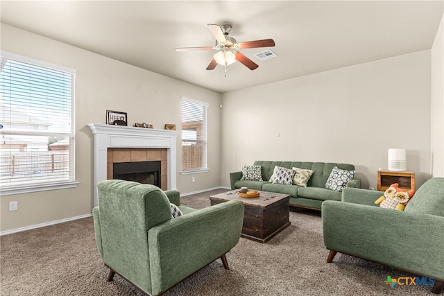 carpeted living room with plenty of natural light, ceiling fan, and a tile fireplace