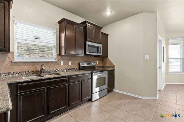 kitchen with stainless steel appliances, sink, tasteful backsplash, light tile patterned floors, and dark brown cabinets