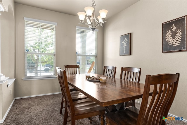 dining area with dark colored carpet and a notable chandelier