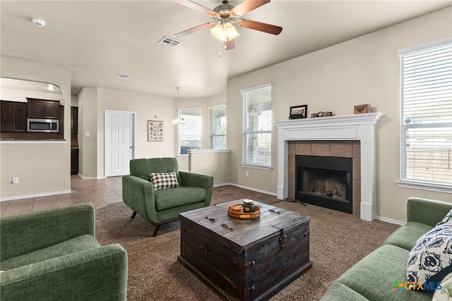 carpeted living room featuring plenty of natural light, ceiling fan, and a tile fireplace