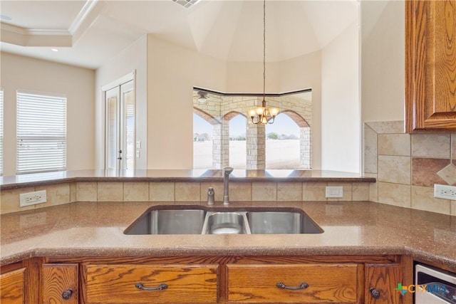 2747 Hester Way, Salado, TX 76571 - kitchen featuring a sink, brown cabinets, healthy amount of natural light, backsplash, and ornamental molding