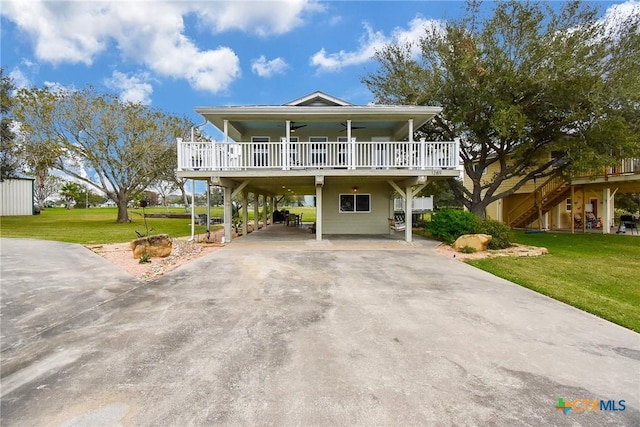 beach home with ceiling fan, a front lawn, and a carport