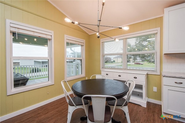 dining area featuring a chandelier, crown molding, dark wood-type flooring, and vaulted ceiling