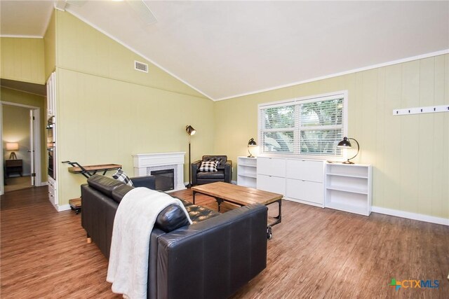 living room featuring hardwood / wood-style flooring, high vaulted ceiling, ornamental molding, and wood walls