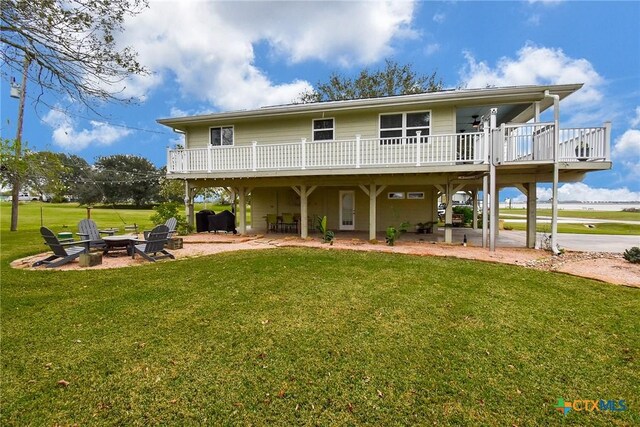 rear view of property featuring a patio area, a yard, a deck, and an outdoor fire pit